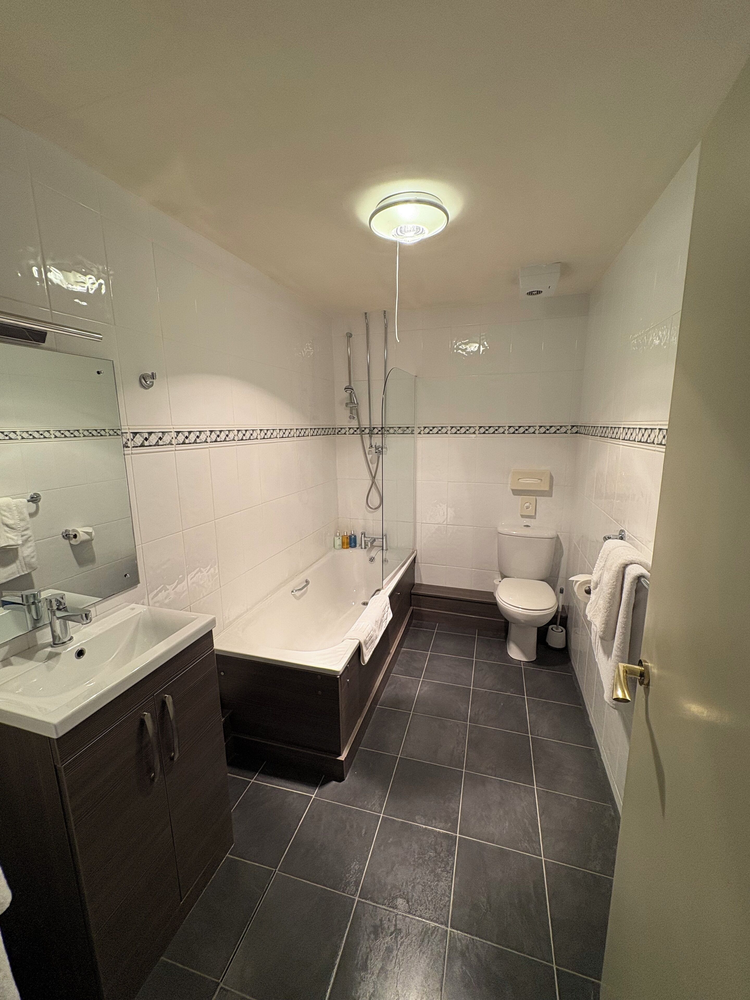 A modern bathroom with a bathtub, toilet, and sink.