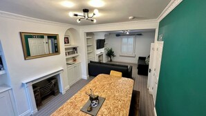 A compact living space with a dining area, a fireplace, a television, and a green accent wall. - Batheaston Terrace (Batheaston)