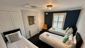 A hotel room with two single beds, a radiator, a chair, and a window with blinds. - Batheaston Terrace (Batheaston)