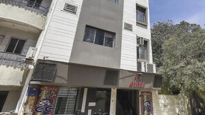 A multi-story building with balconies, a central entrance, and a sign with non-English text. - Hotel Atithi - Opposite Shreeji Hospital (Rajkot)