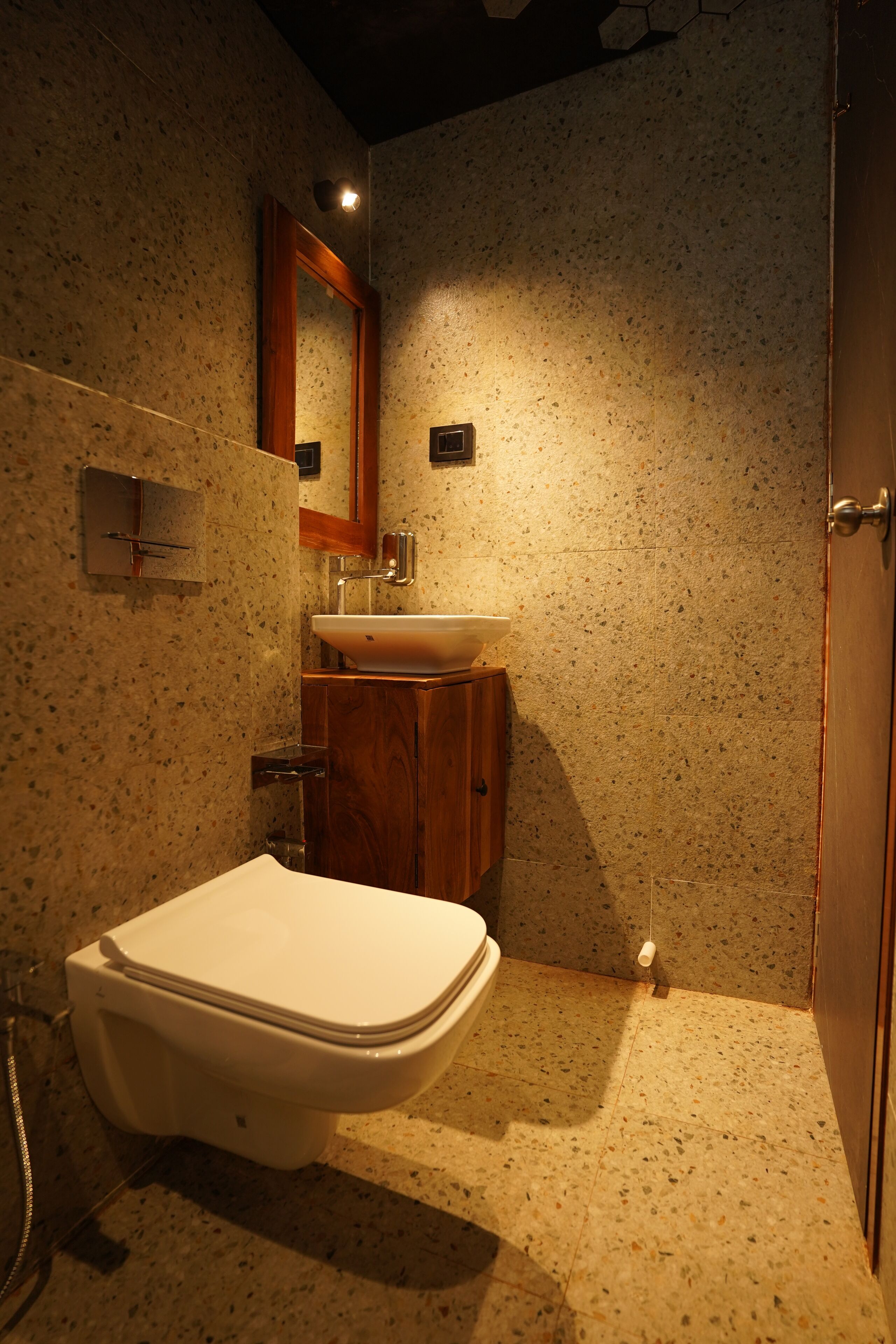 A bathroom with a white toilet, a wooden cabinet, a sink, and a mirror.