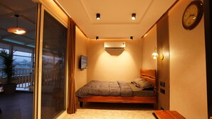 Un dormitorio con cama, mesita de noche, aire acondicionado y un reloj en la pared.