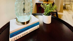 Ein Tisch mit einer Lampe, einem Blumentopf und einem Stapel Bücher.