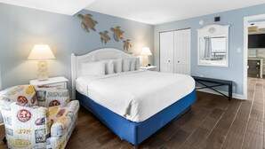 A bedroom with a bed, two bedside tables with lamps, a bench, and a wall with decorative turtle artwork. - Ocean View Retreat: Includes Breakfast 14th Flr (Myrtle Beach)