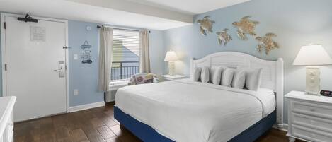 A bedroom with a large bed, a window with curtains, a nightstand with a lamp, and a wall with turtle decorations.