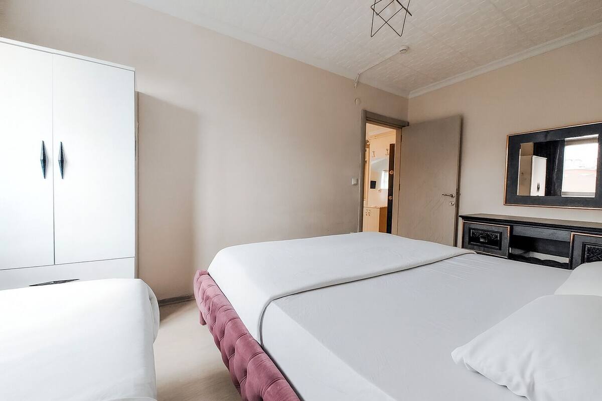 Un dormitorio con dos camas, un armario y un espejo.
