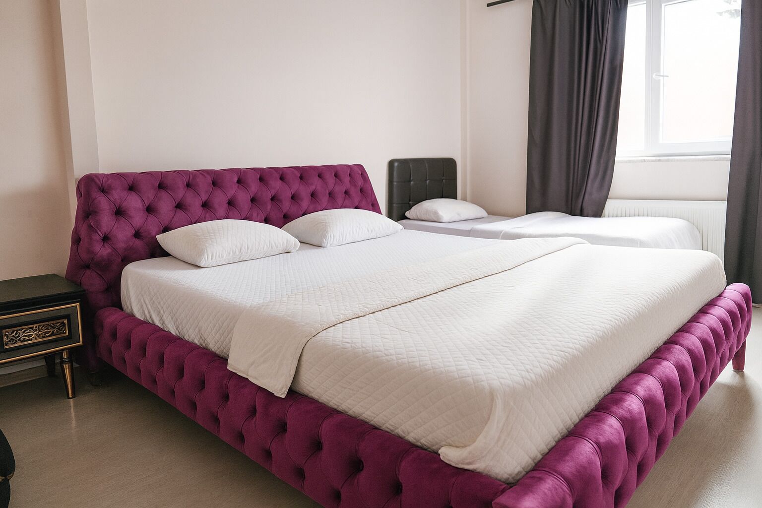 Una cama doble con cabecera capitonada en una habitación de hotel.
