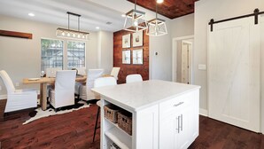 A modern dining area with a wooden ceiling, white furniture, and a central island.