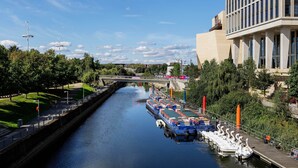 A canal with boats docked on the right, a bridge in the background, and a modern building on the right. - Boho-Chic Escape, by Veeve (London)