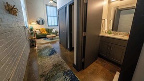 Une cuisine moderne avec des meubles de couleur sombre, un grand miroir et un plan de travail doté d’un évier et d’un robinet.