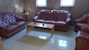 Una sala de estar con un amplio sofá de cuero capitonado, una mesa de centro de madera y una mesita auxiliar con velas.