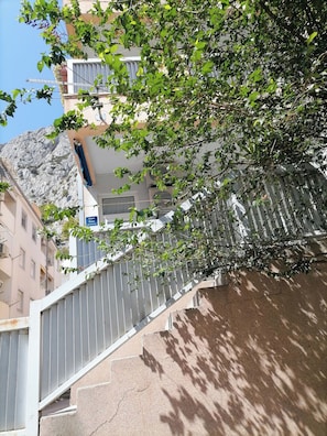 Ein Gebäude mit einer Treppe, einem Metallgitter und einem Baum mit grünen Blättern.