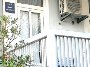Ein Gebäude mit einem Schild, das es als Apartment kennzeichnet, einem Fenster mit Ausblick und einer Klimaanlage.