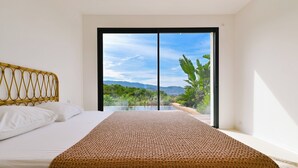 A bedroom with a bed, a view of greenery and mountains through a sliding door, and a large window. - SUMPTUOUS MODERN VILLA (Pietrosella)