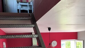 Eine Treppe mit Metallgeländer, die zu einem Raum mit roten Wänden führt.