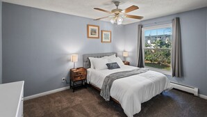 A bedroom with a bed, nightstands, a ceiling fan, and a window with curtains. - Tranquil 2BR Apt Mpls - 8075 Apt 4 (Minneapolis)