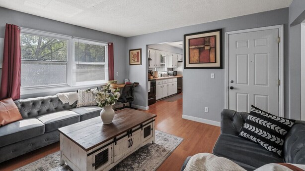 A living room with a sofa, coffee table, and a couch. There is a kitchen in the background. - Tranquil 2BR Apt Mpls - 8075 Apt 4 (Minneapolis)