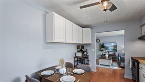 A dining area with a wooden table set for four, a ceiling fan, and a kitchen in the background. - Tranquil 2BR Apt Mpls - 8075 Apt 4 (Minneapolis)