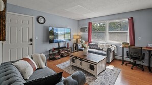 A living room with a sofa, coffee table, TV, and a desk with a chair. - Tranquil 2BR Apt Mpls - 8075 Apt 4 (Minneapolis)