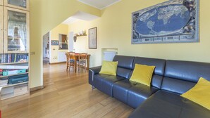 A living room with a dark blue leather sofa, wooden floor, and a world map on the wall. - Camaiore House With Pool, La Casa Dei Ricci (Camaiore)