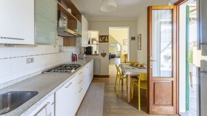 A modern kitchen with white cabinets, a stainless steel sink, and a wooden dining table with yellow chairs. - Camaiore House With Pool, La Casa Dei Ricci (Camaiore)