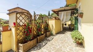 A stone-paved courtyard with wooden planters and a lattice gate. - Camaiore House With Pool, La Casa Dei Ricci (Camaiore)