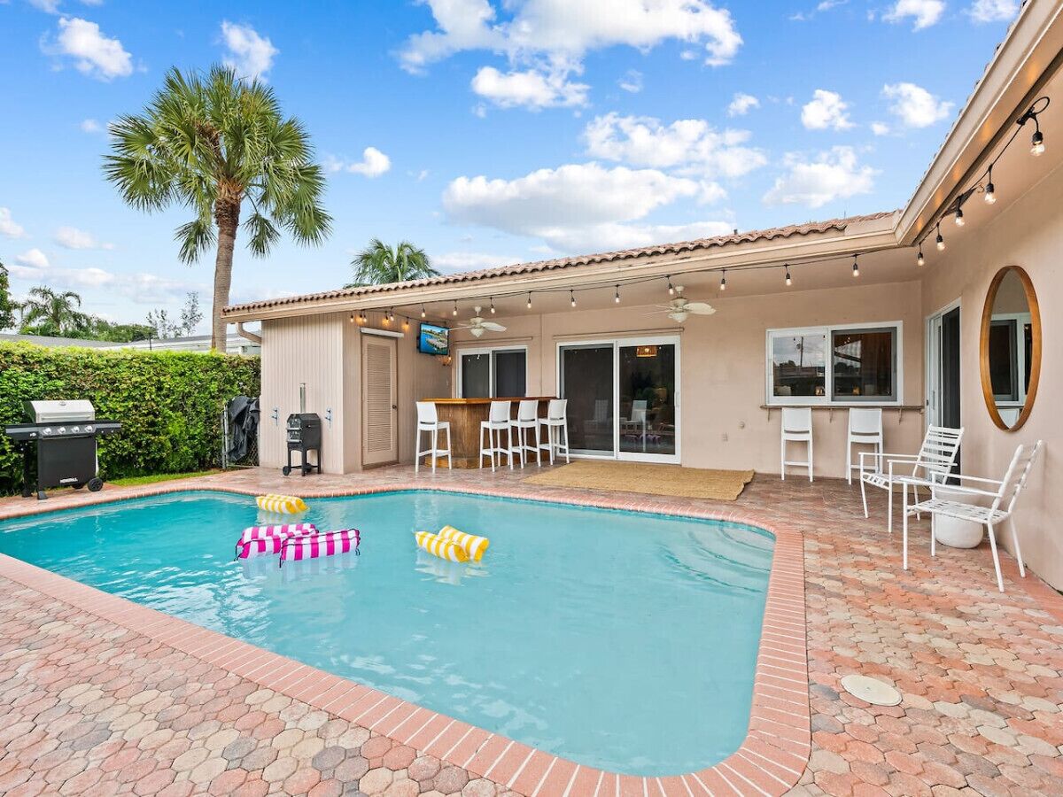 A backyard with a swimming pool, patio furniture, and a barbecue area.