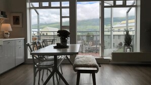 Cocina moderna con una mesa de comedor, sillas y un banco. Hay un ventanal con vistas al campo.