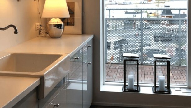 Una cocina moderna con un amplio ventanal, un lavamanos y una encimera con una lámpara y objetos decorativos.