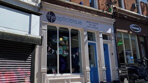 A multi-story building with a storefront named 'the opticians.ie' on the ground floor.
