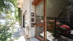Entrada de um edifício com porta de vidro, caixa de correio e um pequeno degrau que leva à porta.