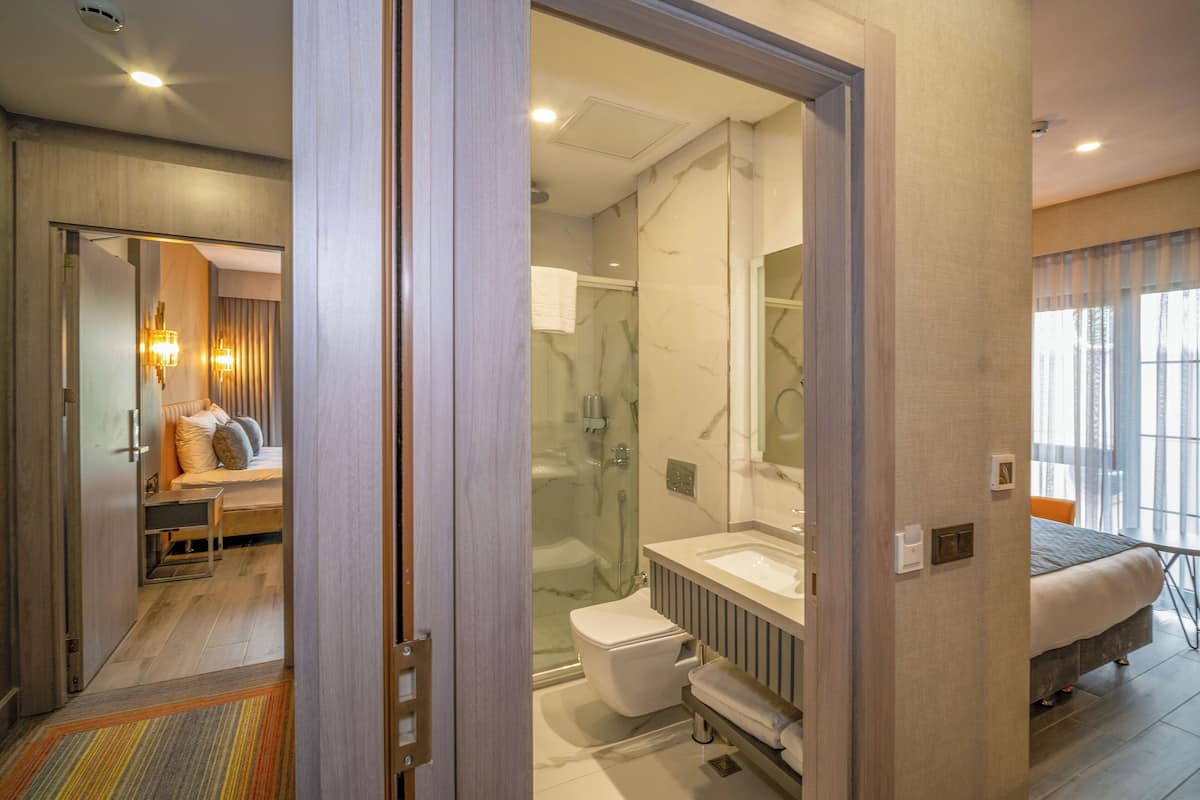 A modern hotel room with a shower, toilet, and a bed.