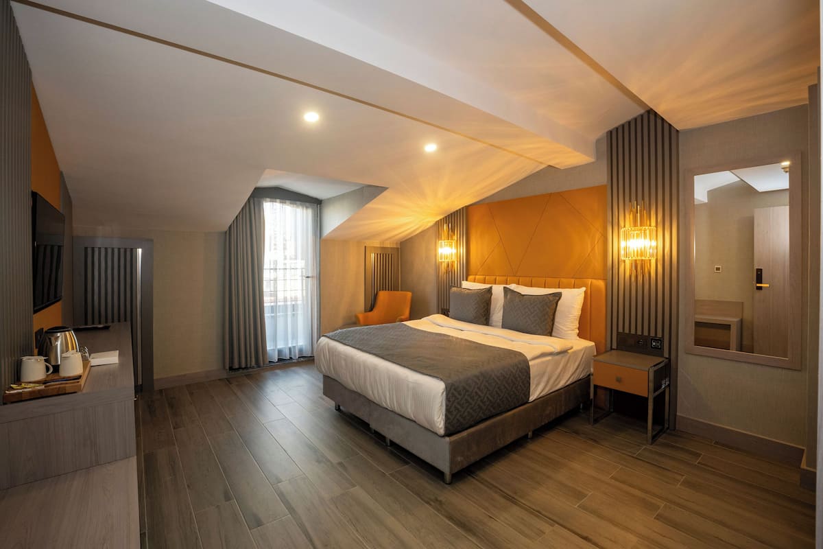 A modern bedroom with a large bed, a bedside table, a mirror, and a window with curtains.