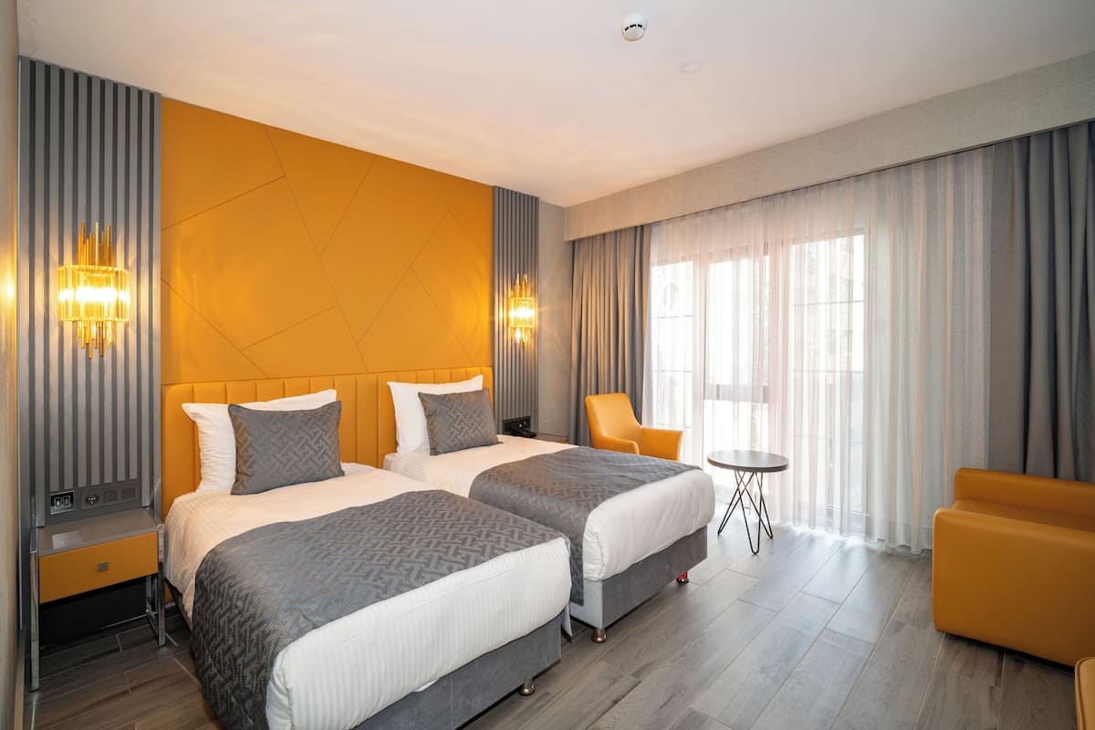 A hotel room with two beds, a sofa, a small table, and a chair.