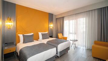 A hotel room with two beds, a sofa, a small table, and a chair.