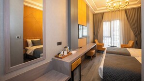 A hotel room with a large mirror, a desk with a tray of items, two beds, a chandelier, and a TV. - İcon Hotel Bomonti (Istanbul)
