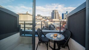 A balcony with a table and chairs, a glass door, and a city view. - İcon Hotel Bomonti (Istanbul)