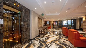 A lobby with marble flooring, red seating, and an elevator. - İcon Hotel Bomonti (Istanbul)