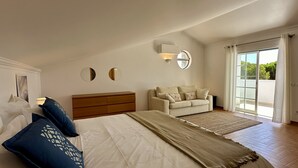 Une chambre avec un grand lit, un canapé, une commode et une fenêtre avec des rideaux.