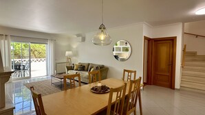 Un coin repas avec une table et des chaises en bois, un canapé, une lampe et un escalier menant à une autre pièce.