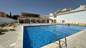 Une piscine avec des chaises longues et un espace couvert doté d’un toit.