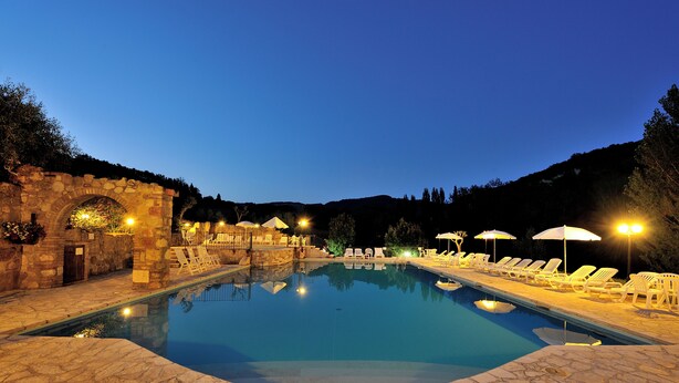 A swimming pool with lounge chairs and umbrellas, surrounded by stone walls and a stone archway. - Cozy three-room apartment in the Umbrian countryside. (Umbria)