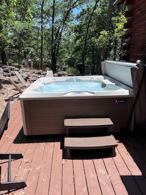 A hot tub on a wooden deck with a bench in front, surrounded by trees. - Camp Allswell - Cozy Loft Cabin Getaway-Fireplace (Eureka Springs)