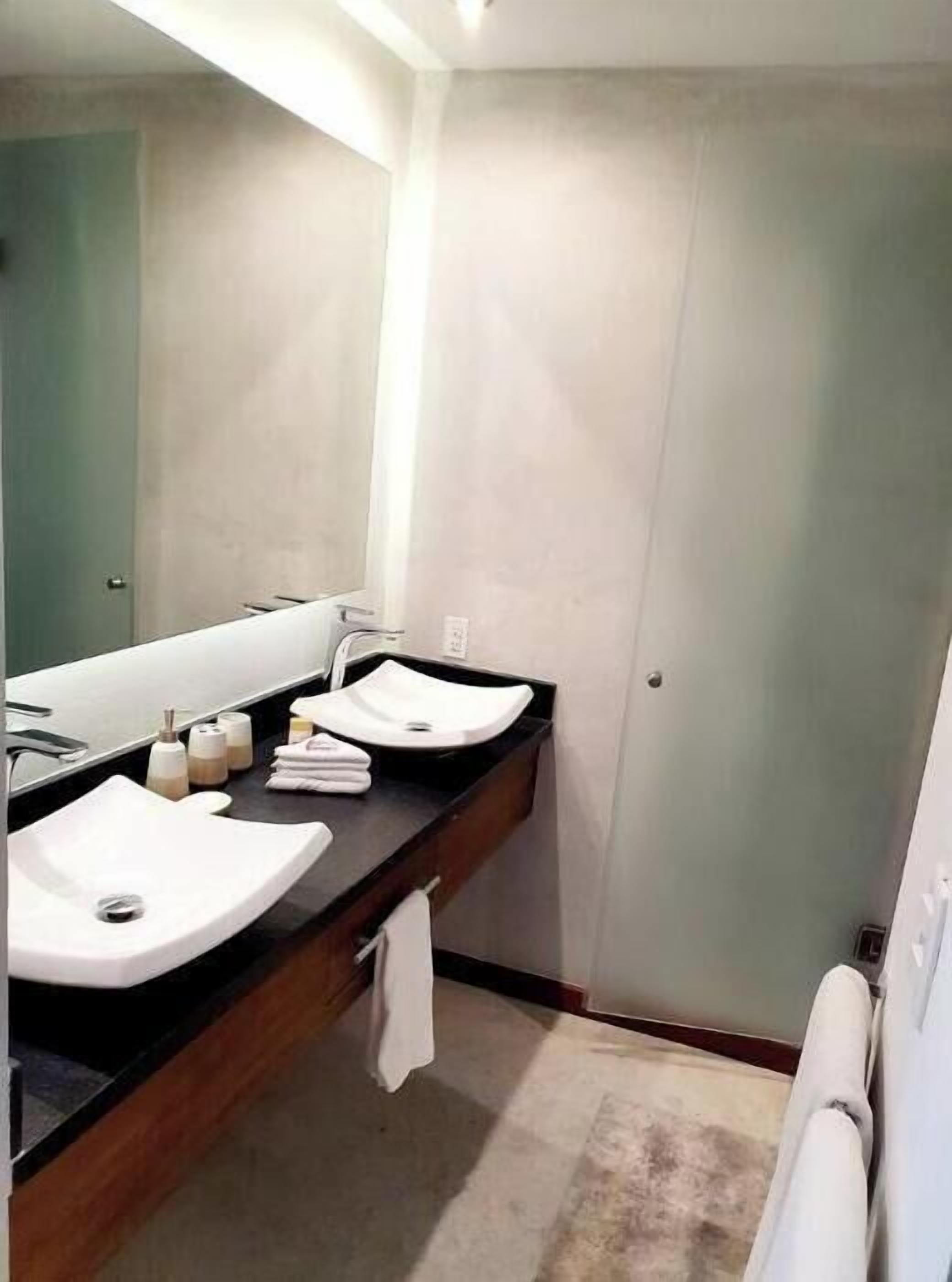 Une salle de bain moderne avec deux lavabos, un grand miroir et un porte-serviettes.