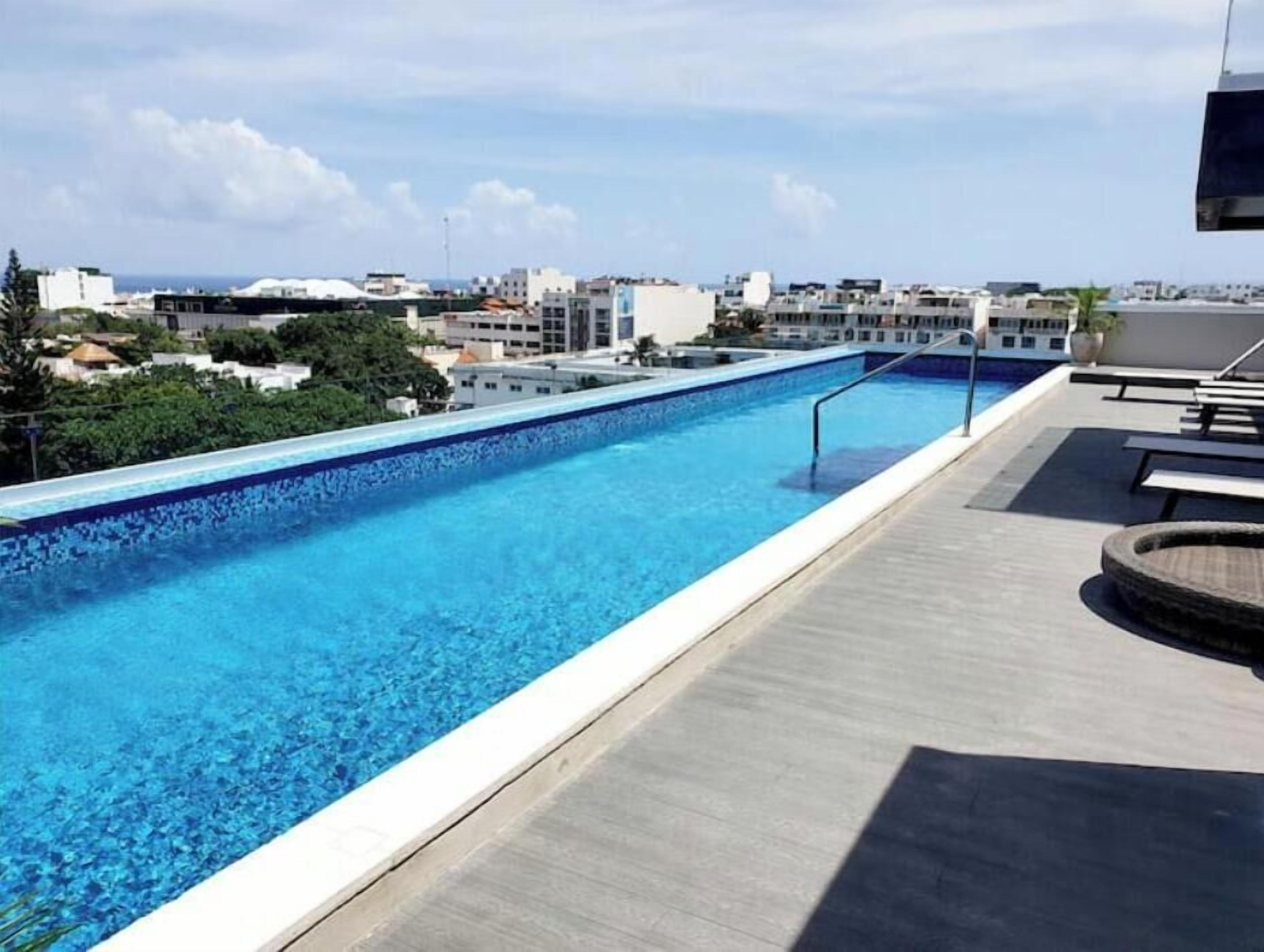 A rooftop swimming pool with a clear view of the cityscape in the background.