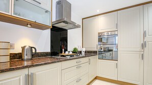 Eine moderne Küche mit weißen Schränken, Granit Arbeitsplatten und Edelstahlgeräten, inklusive eingebautem Backofen.