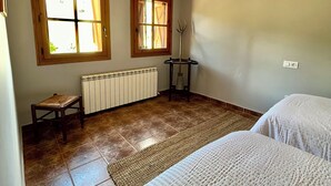 Habitació amb dos llits, un radiador, una finestra i una taula petita.