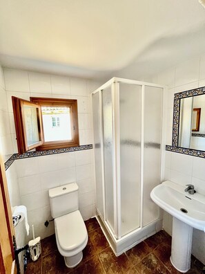 A bathroom with a toilet, a shower enclosure, and a sink.