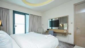 Ein Hotelzimmer mit einem großen Bett, einem Schreibtisch, einem Fernseher und einem Spiegel.
