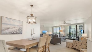 A spacious living area with a dining table, chairs, a sofa, and a TV. - Beachfront 2BR condo with pool, WiFi, and heated pool on Marco Island. (Marco Island)